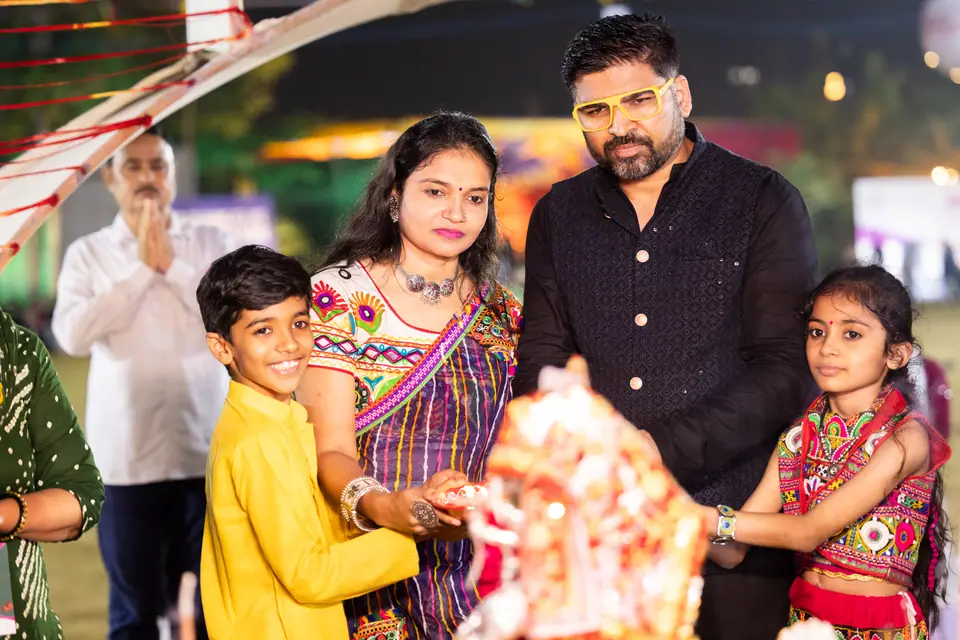 A family doing aarti together, the children in yellow and red
