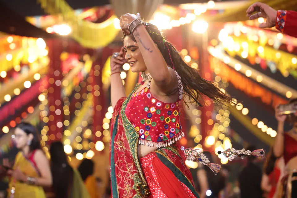 A dancer with her hair flying under strings of warm festival lights