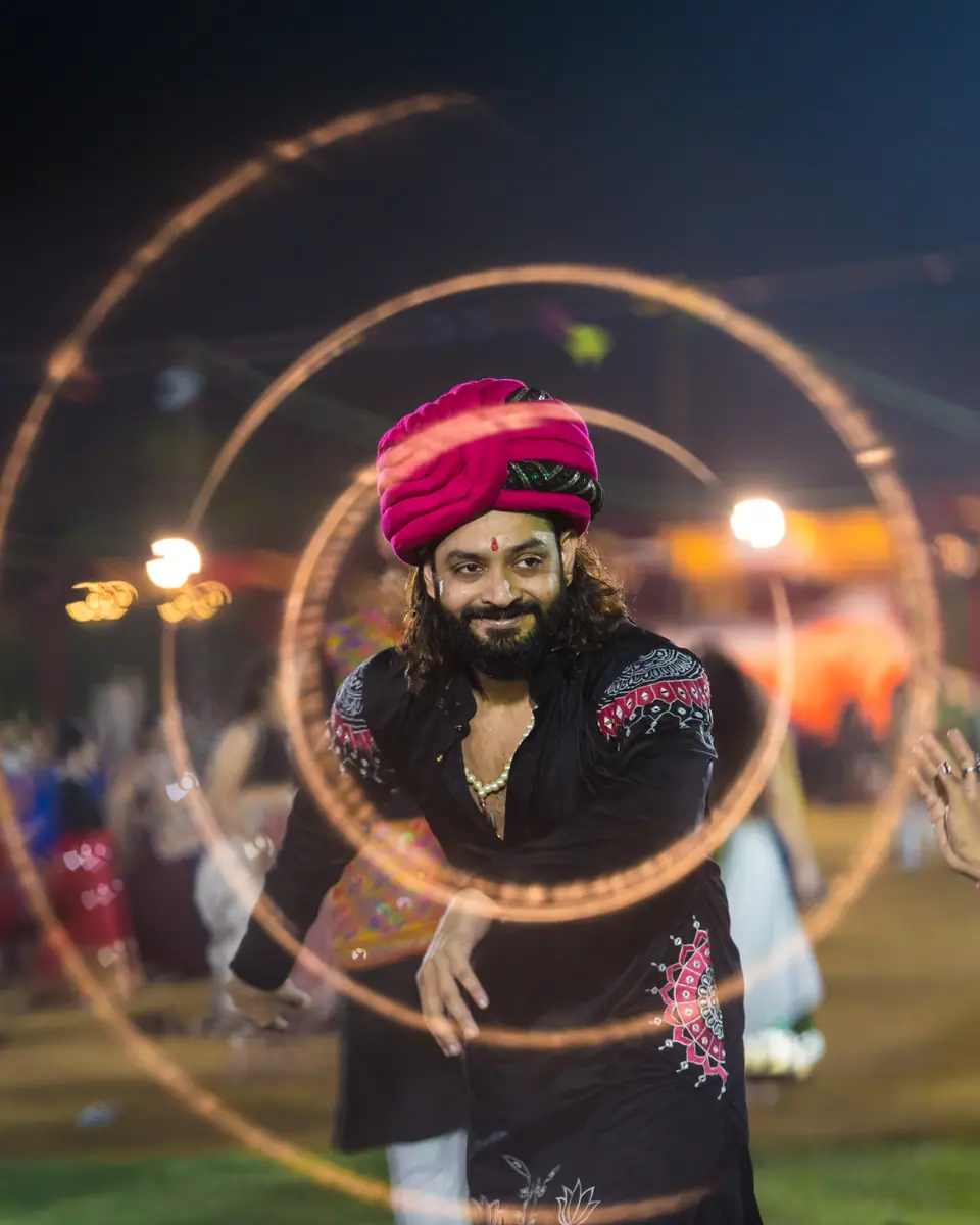 A man in a pink turban smiling through rings of light