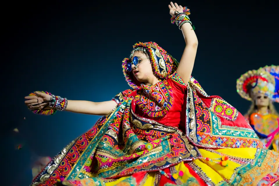 A dancer in a red and gold chaniya choli spinning, one arm raised