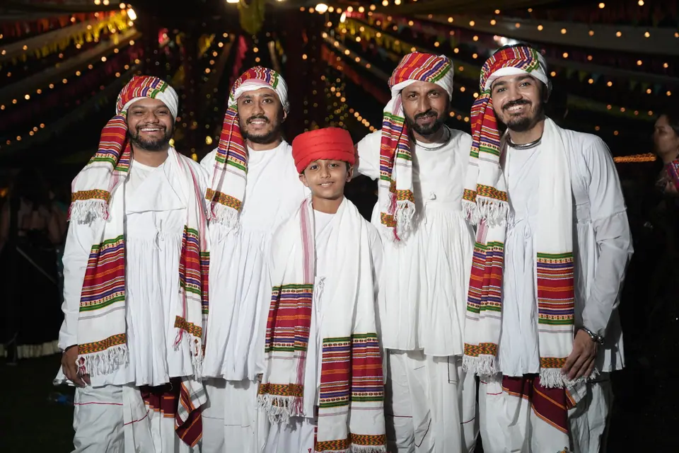 A group in white kediyus, striped shawls and turbans posing on the ground
